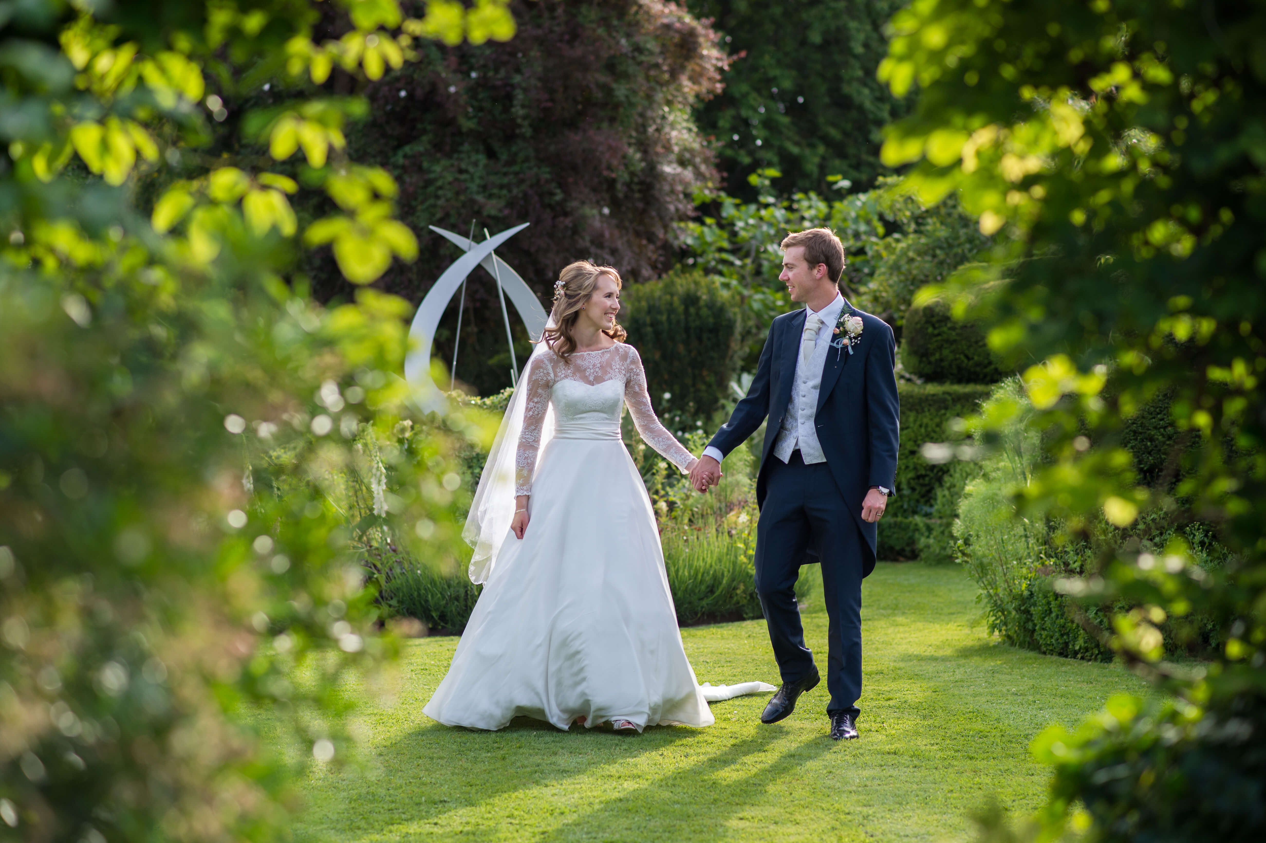 A bride and groom holding hands in the gardens of chenies manor 